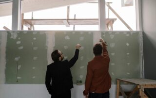 two people working together to repair a wall