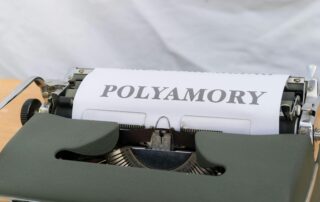 a typewriter with a paper spelling the word polyamory
