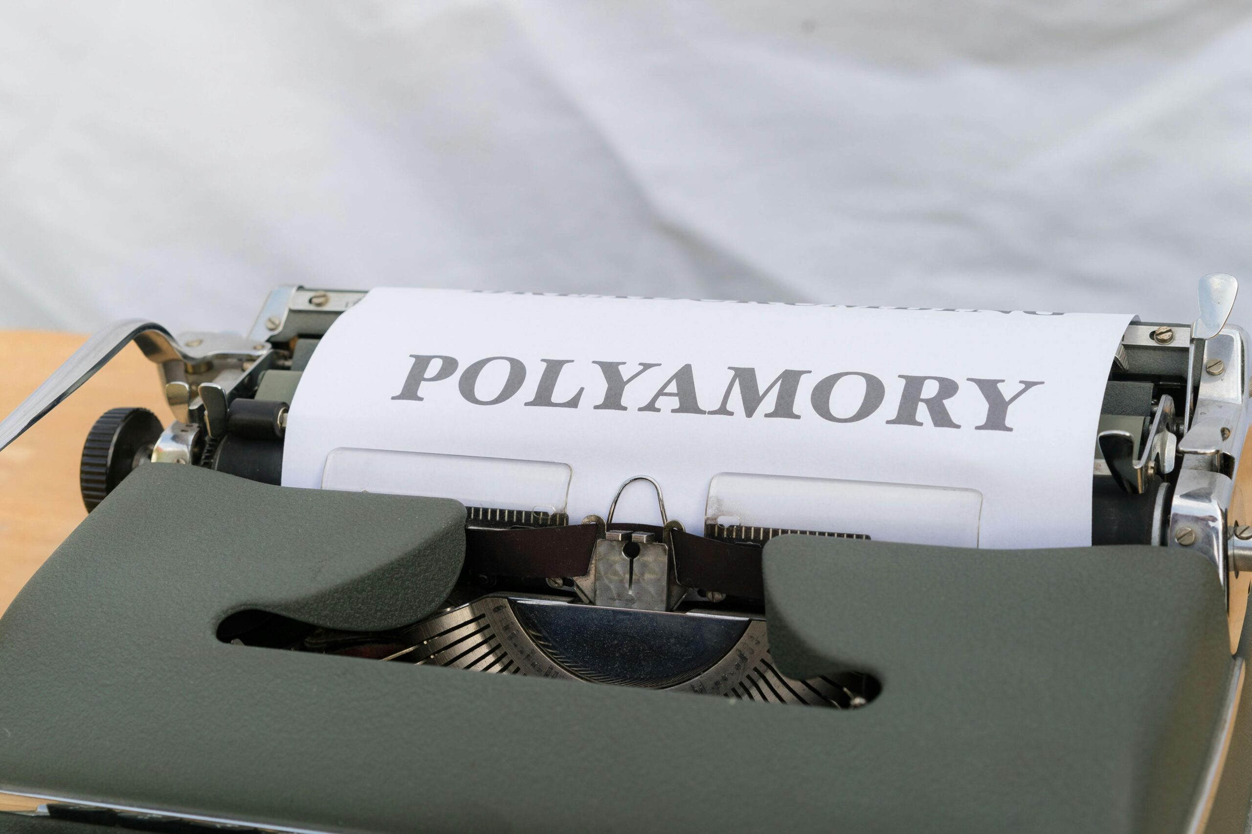 a typewriter with a paper spelling the word polyamory