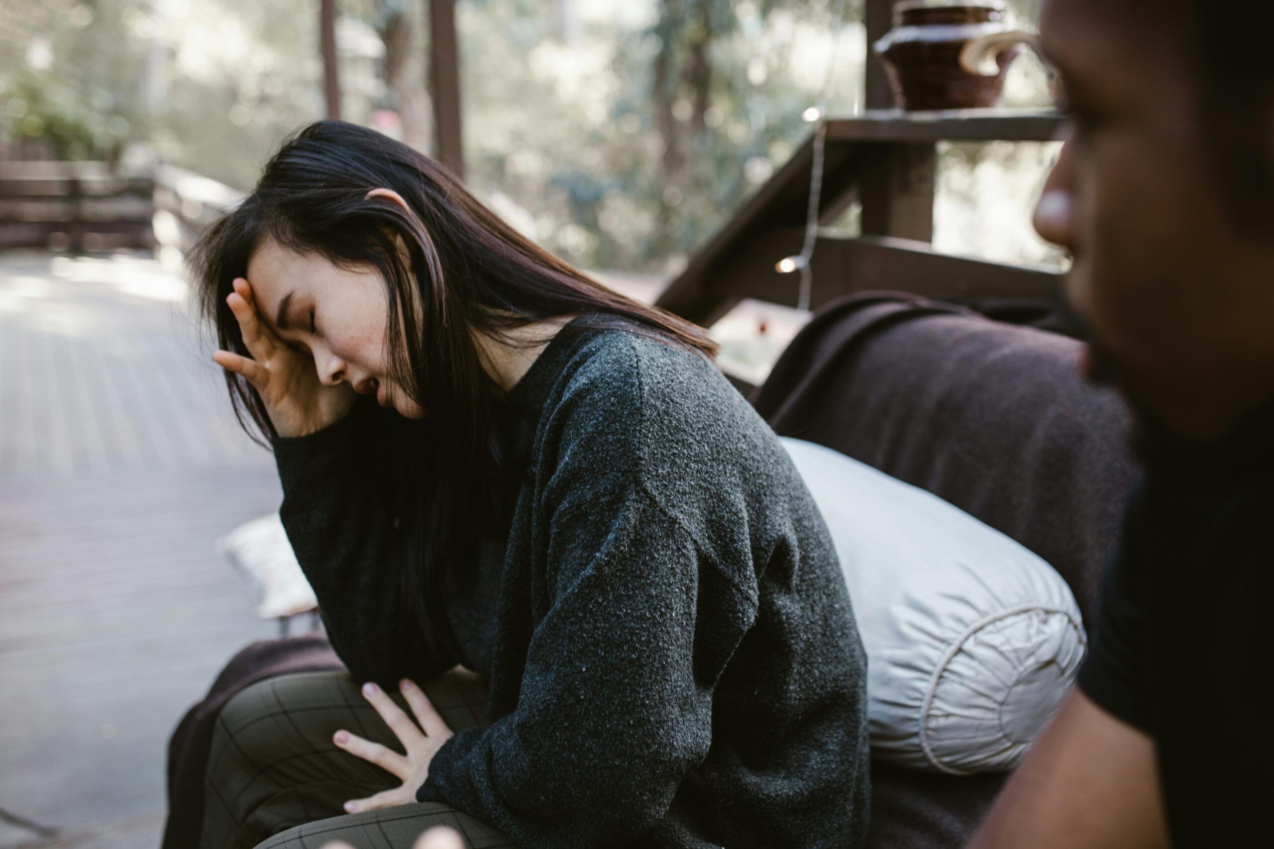 woman and man sitting on couch with head in hands