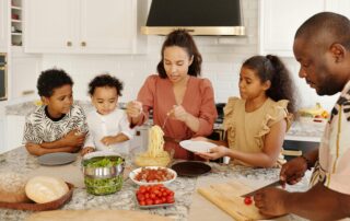 family gathered around a dinner table making spaghetti