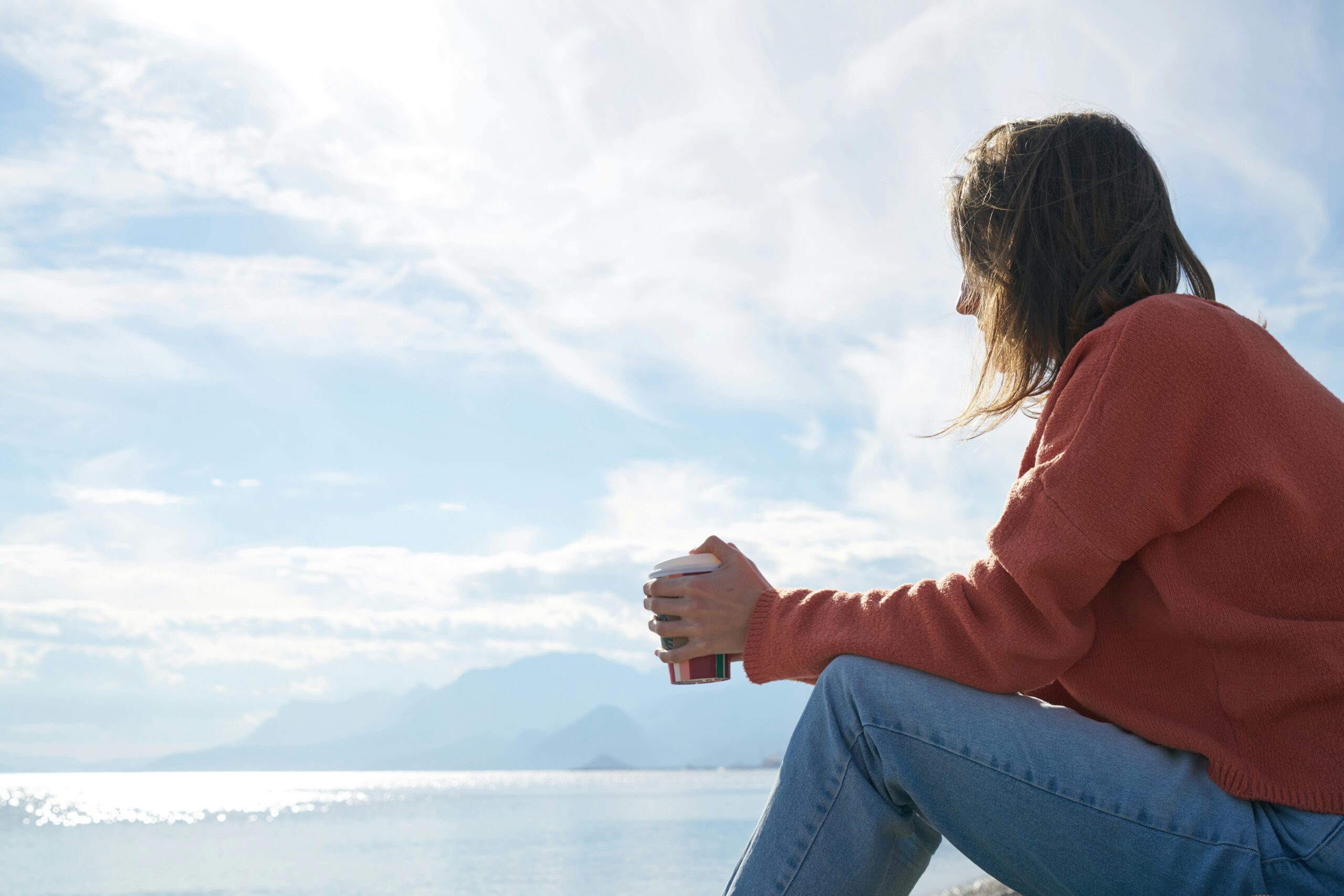 Person reflecting thoughtfully near a window, representing introspection and personal growth in therapy